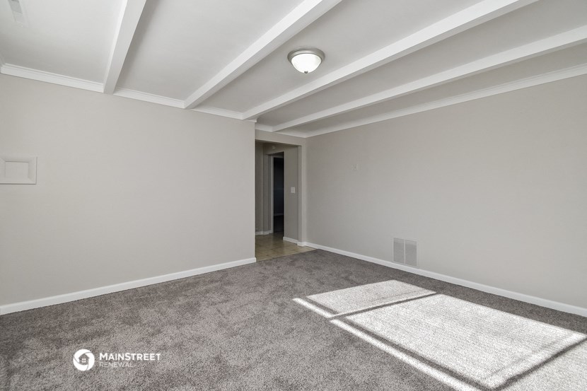 an empty living room with white walls and carpet