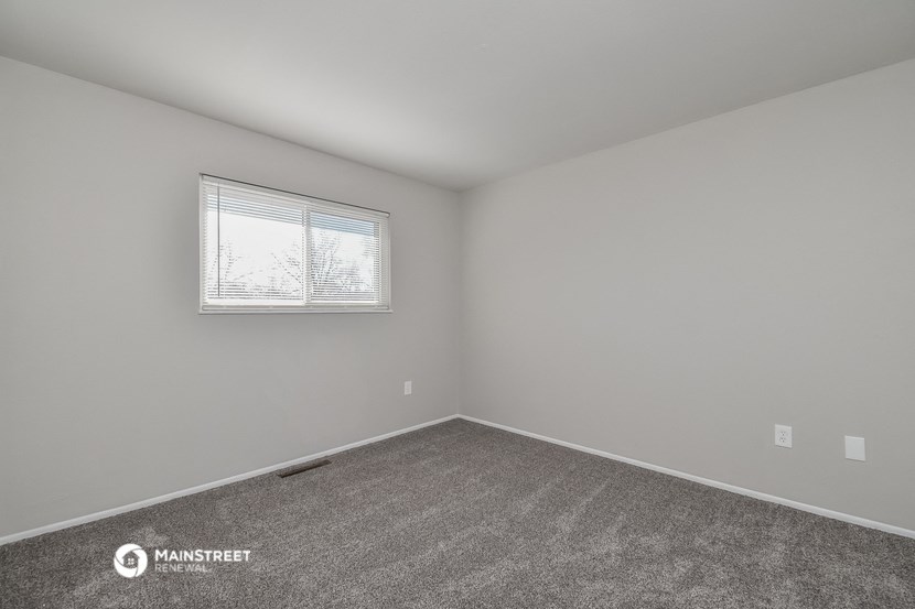 a bedroom with white walls and a window