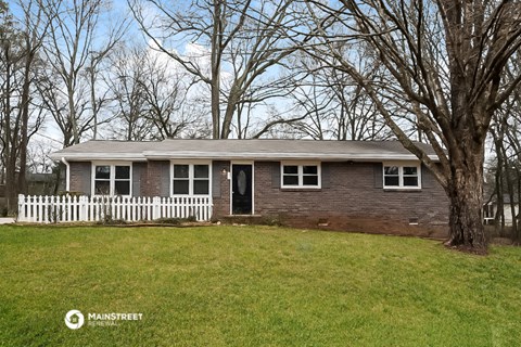 a white picket fence in front of a brick house