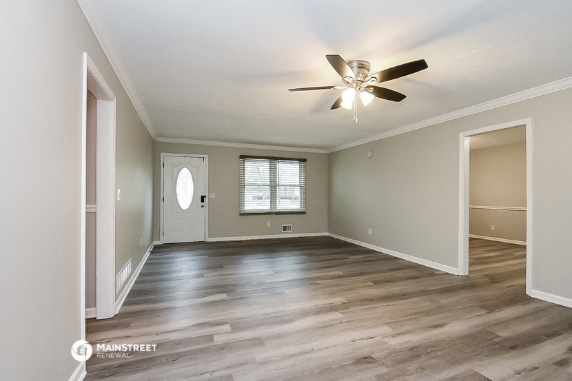 an empty living room with a ceiling fan