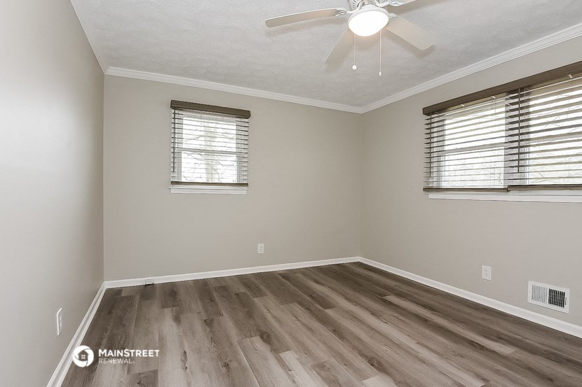 the spacious living room with hardwood flooring and a ceiling fan
