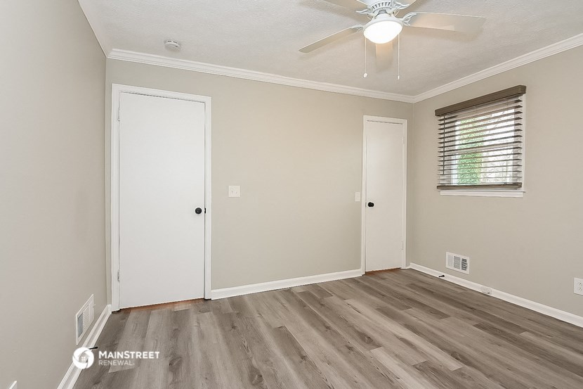 the living room of a white house with wood floors and a ceiling fan