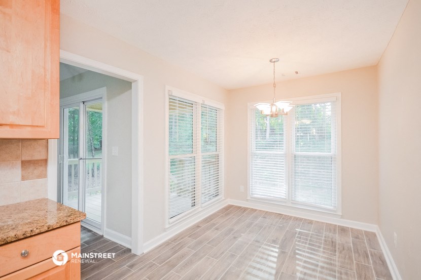 an empty dining room with windows and a kitchen