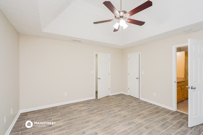 the living room of an empty house with a ceiling fan