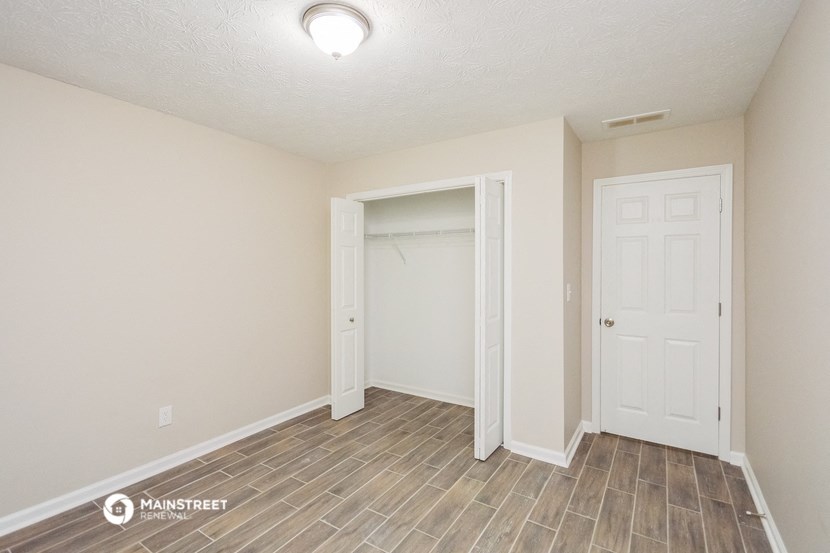 the spacious living room with a closet and a door to the bathroom