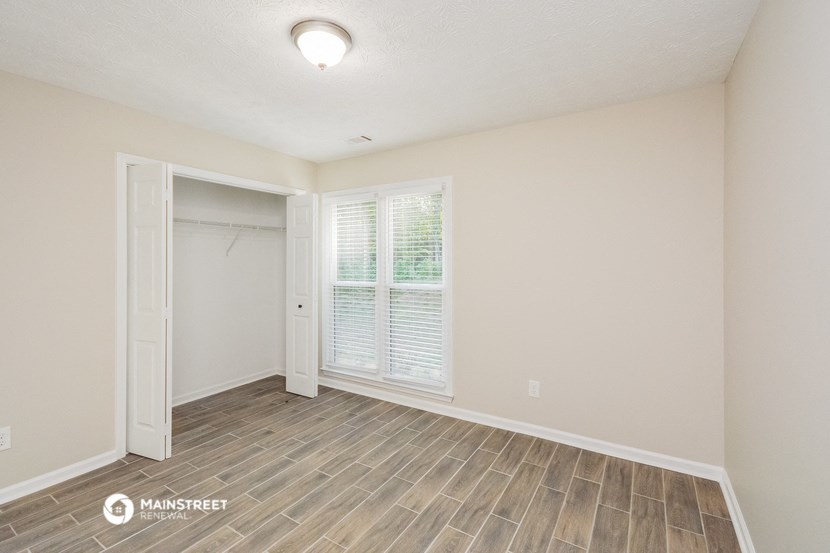 the spacious living room with wood flooring and a door to the closet