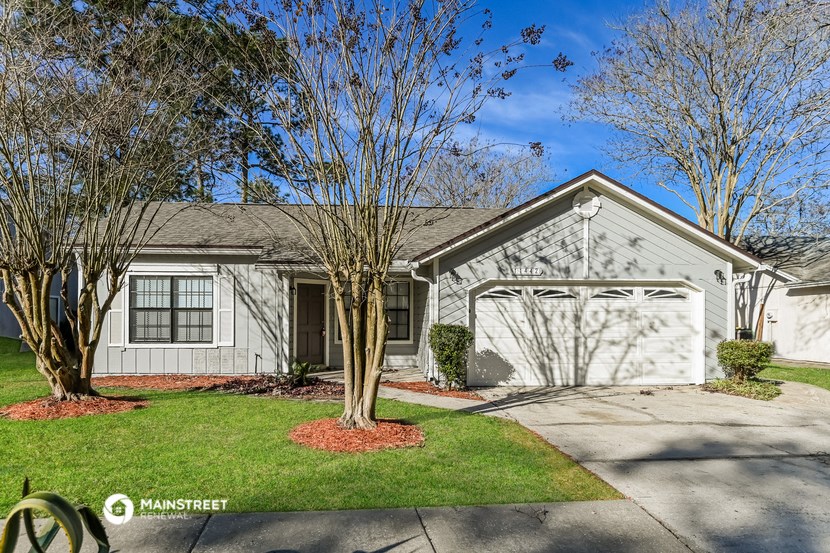 a white house with a driveway and trees in front of it