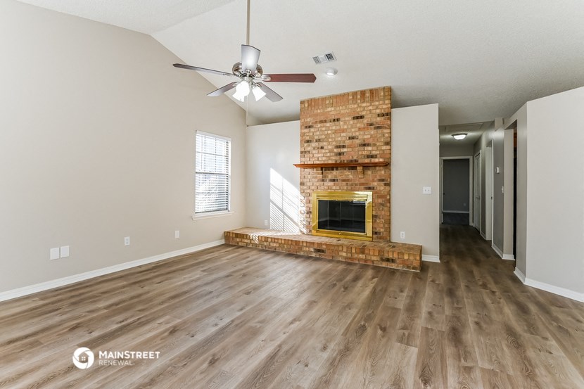 an empty living room with a fireplace and a ceiling fan