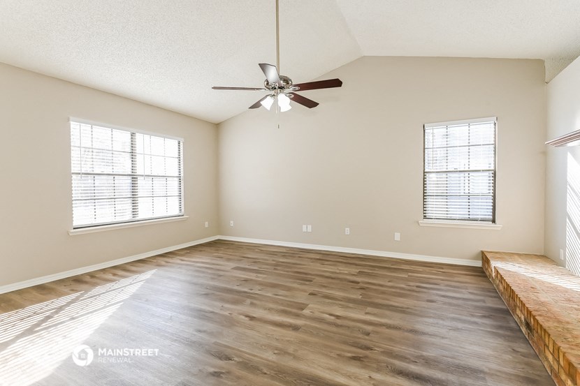the spacious living room with hardwood floors and a ceiling fan