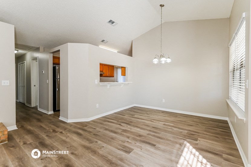 the spacious living room with wood flooring and white walls