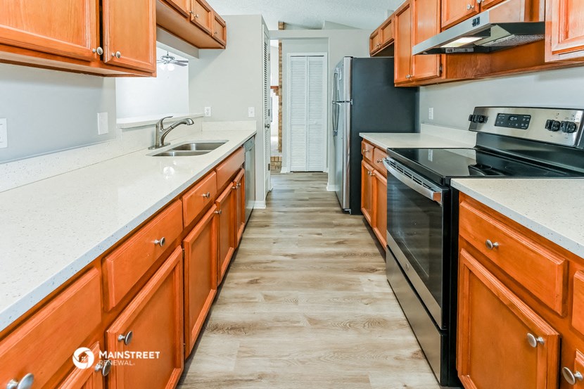 a kitchen with wooden cabinets and white counter tops and black appliances