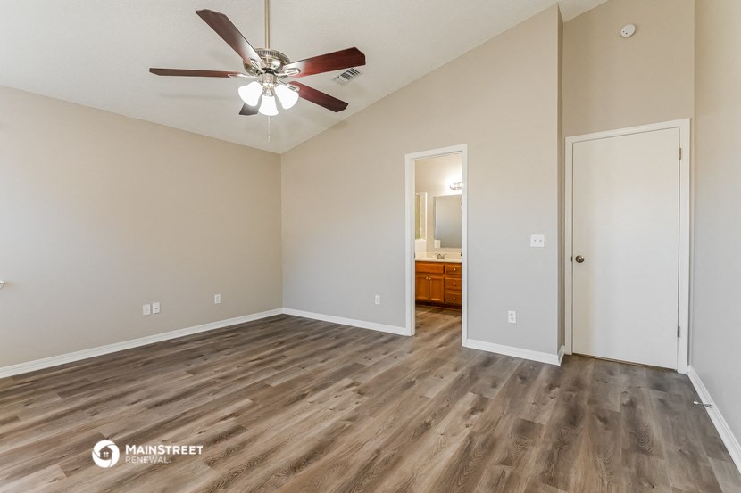 the spacious living room with wood flooring and a ceiling fan