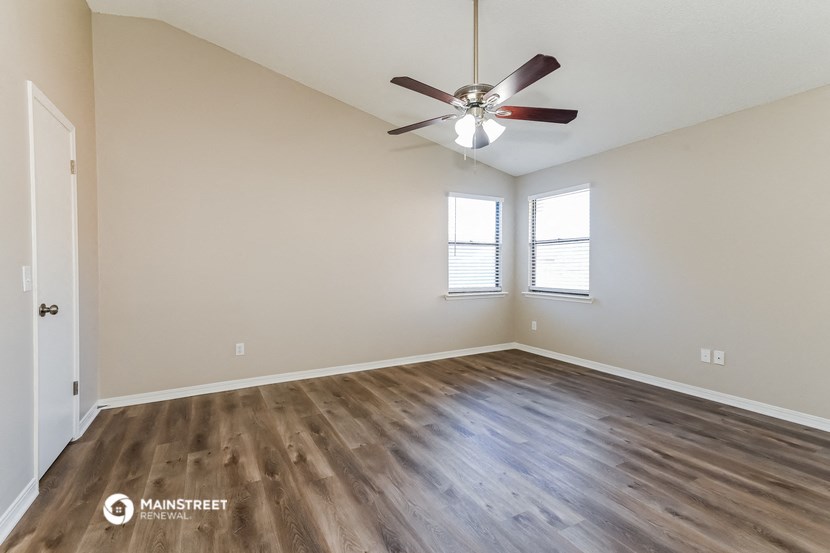the spacious living room with hardwood floors and a ceiling fan