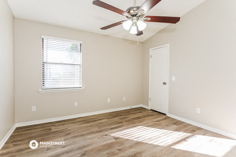 an empty room with a ceiling fan and a window
