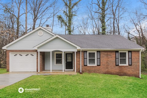 the front of a brick house with a lawn and a white garage