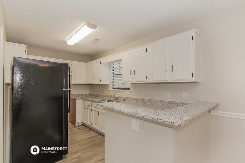 a kitchen with white cabinets and granite counter tops and a black refrigerator