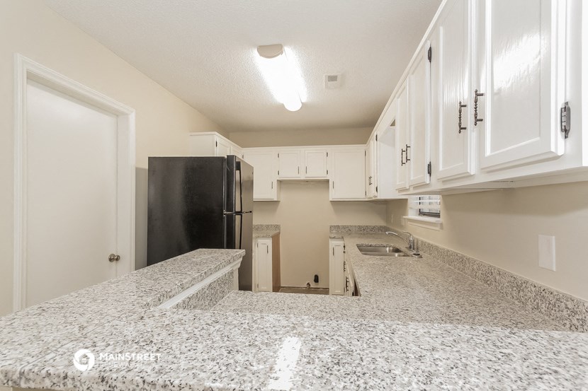 a kitchen with white cabinets and a black refrigerator