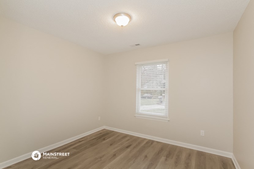the spacious living room with hardwood flooring and a window