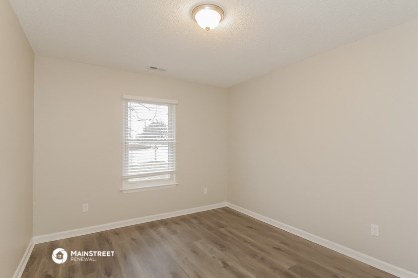 the interior of a bedroom with wood flooring and a window