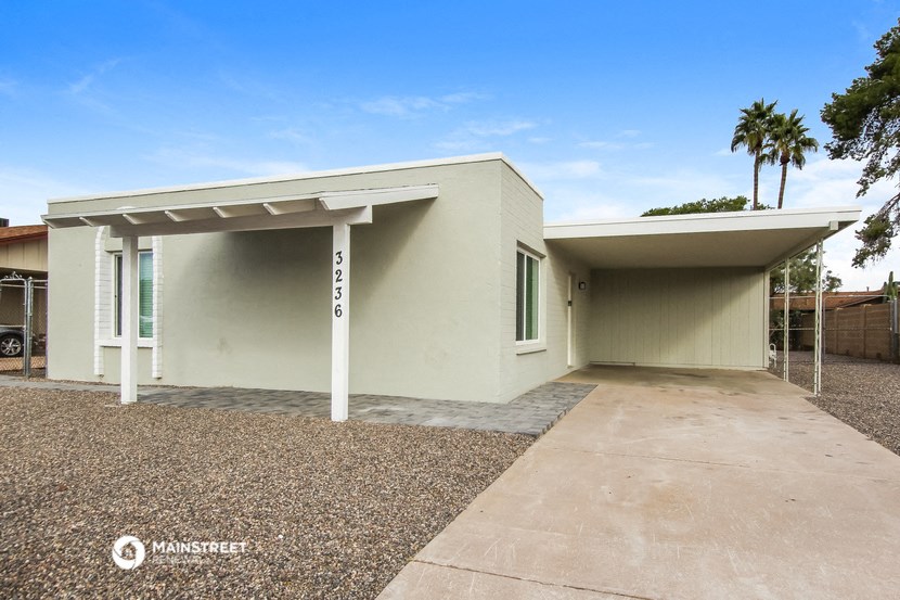 a white house with a driveway and palm trees