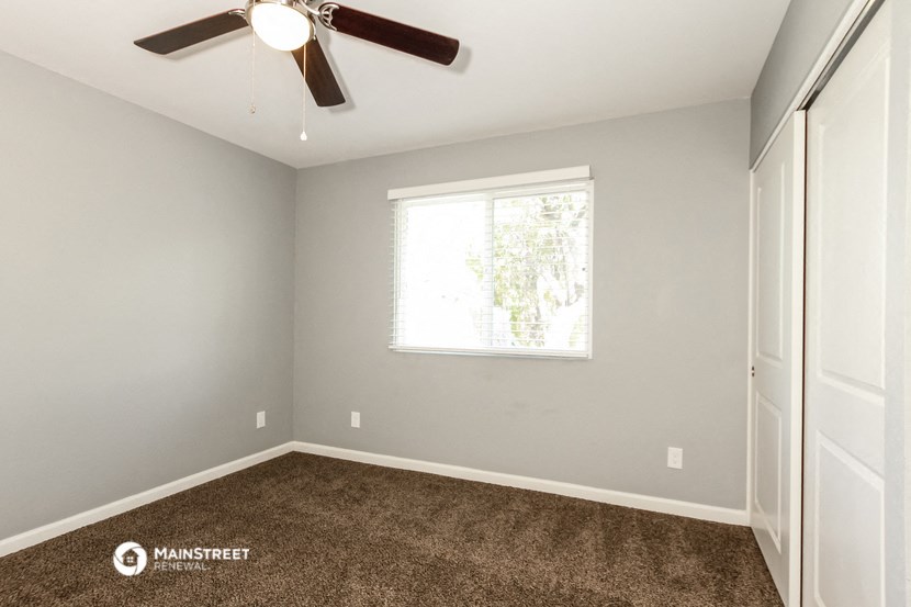 the master bedroom has carpet and a ceiling fan