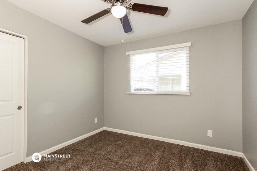 the bedroom has carpet and a ceiling fan