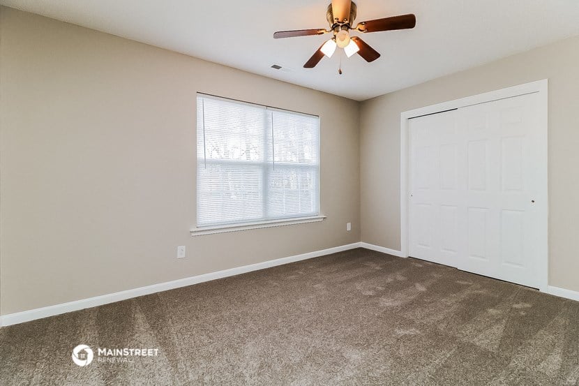 the spacious living room with carpet and a ceiling fan