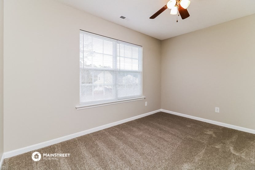 a bedroom with carpet and a large window and a ceiling fan