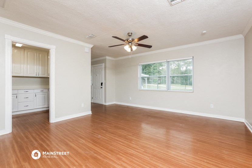 the living room and dining room of a house with wood floors and a ceiling fan