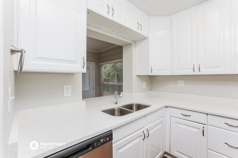 a white kitchen with a sink and white cabinets