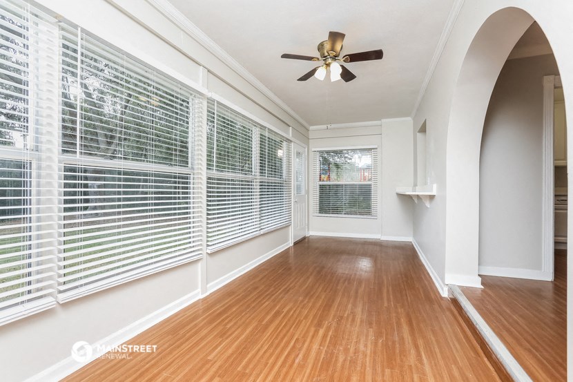 an empty living room with large windows and a ceiling fan