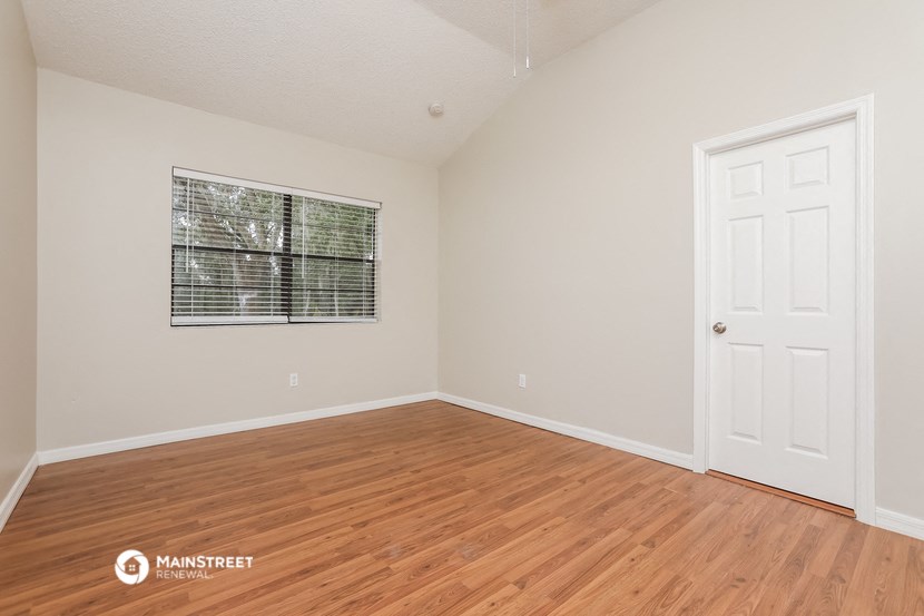 the spacious living room with wood flooring and a white door