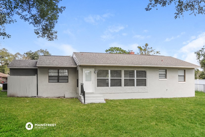 the front of a white house with a yard and grass