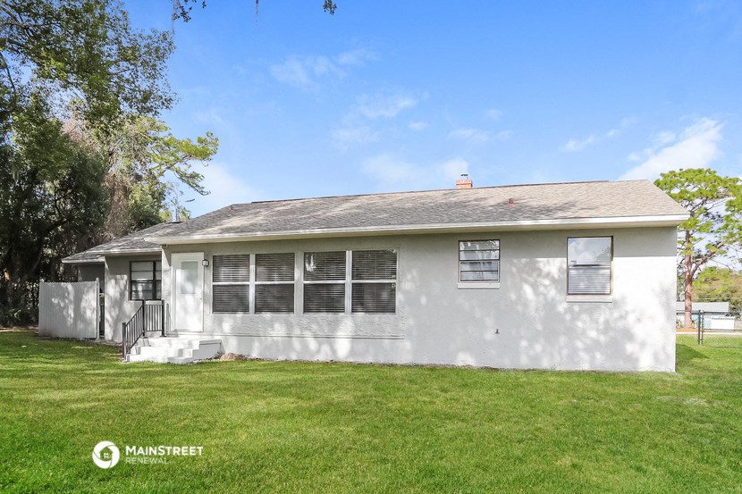 a white house with a grassy yard and a tree