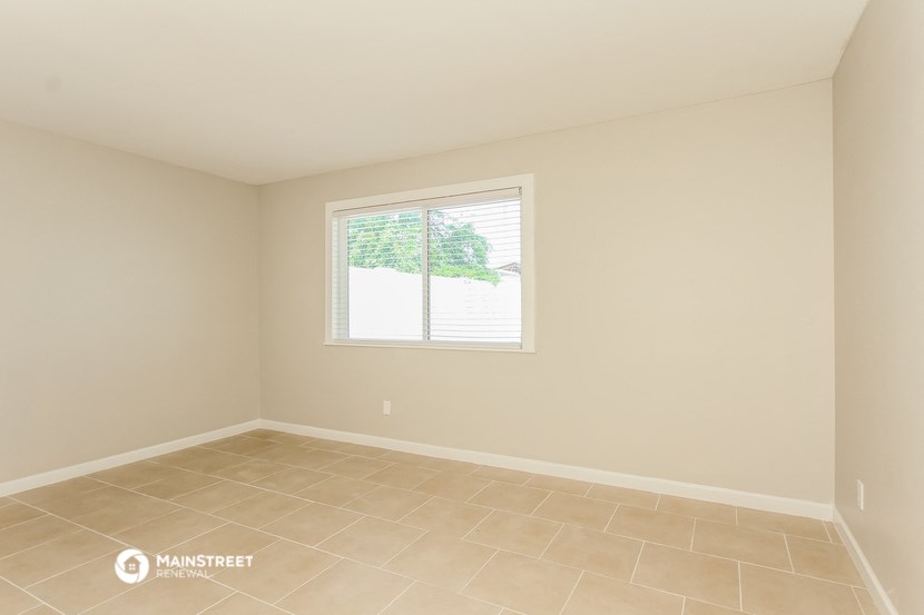 the living room of a home with a large window and tiled floors