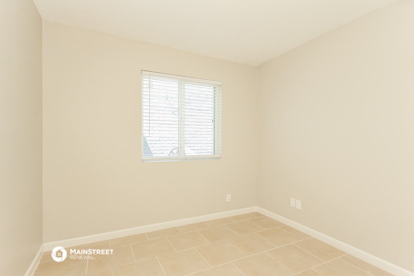 an empty room with a window and a tiled floor