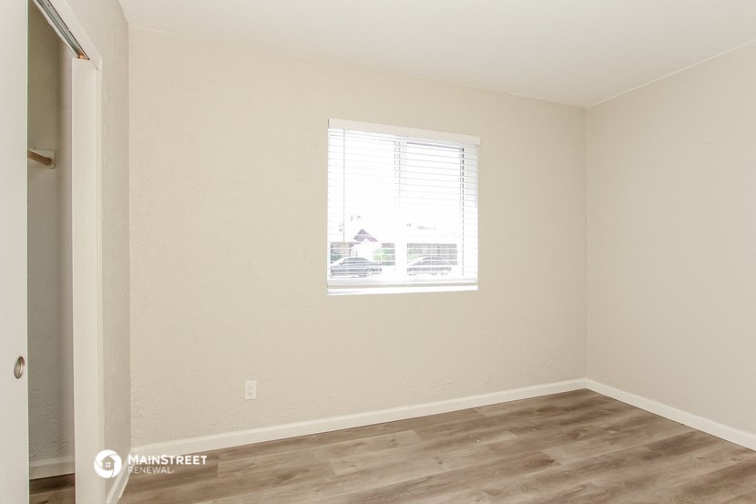 a bedroom with a window and a wooden floor
