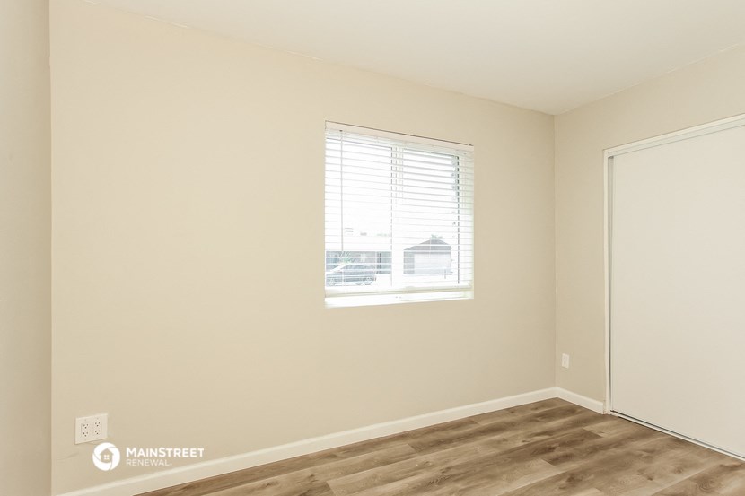 a bedroom with a window and wooden floors and a door