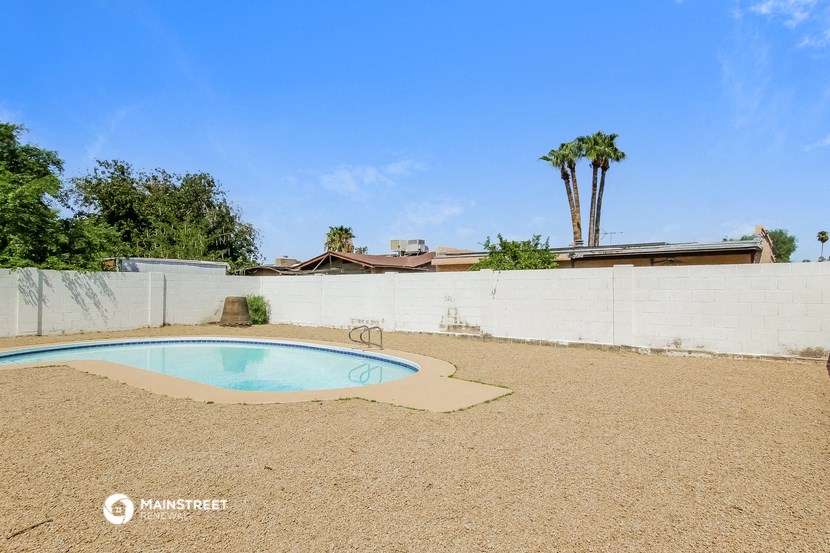 a pool in the backyard of a house with palm trees