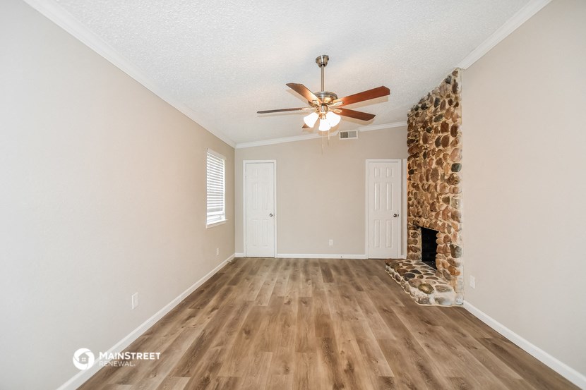 an empty living room with a fireplace and a ceiling fan