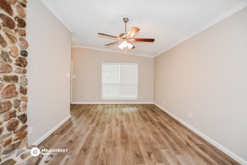 a spacious living room with wood floors and a ceiling fan