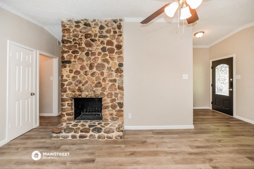 the living room has a stone fireplace and hardwood floors