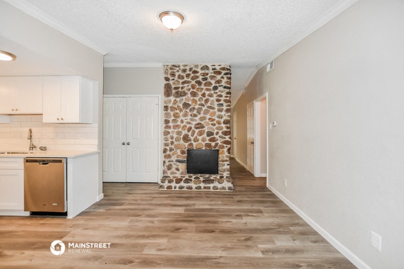 a renovated kitchen with white cabinets and a fireplace with a stone wall