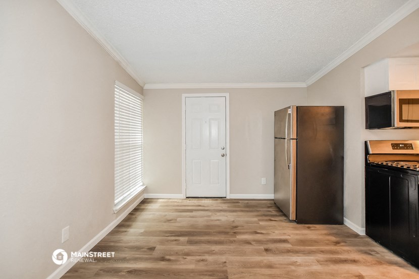 an empty kitchen with a refrigerator and a microwave