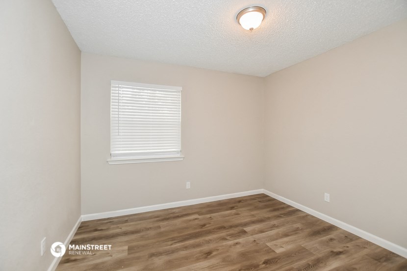 the interior of a bedroom with wood flooring and a window