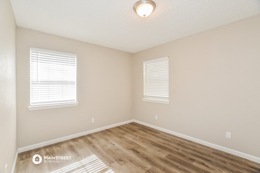 the spacious living room with hardwood flooring and two windows