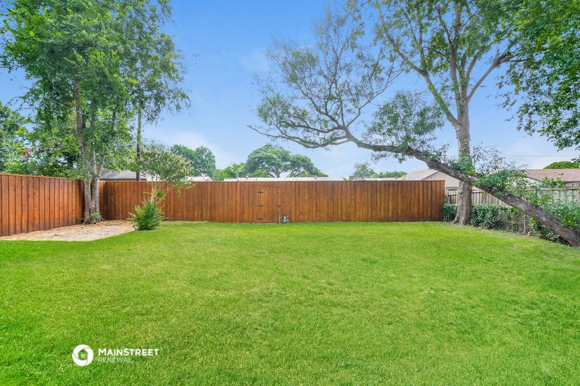 a backyard with a wooden fence and a green lawn