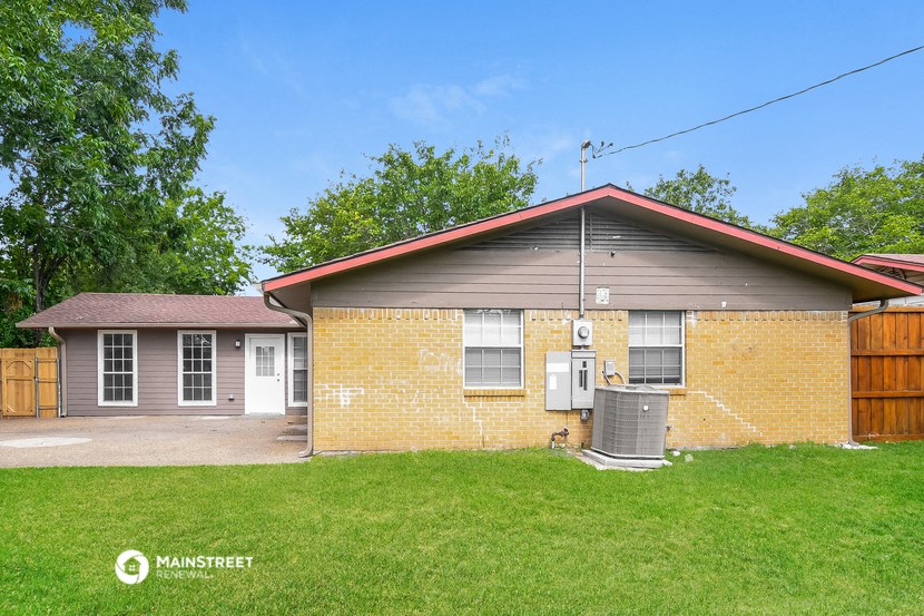 a small brick house with a yard and a backdoor