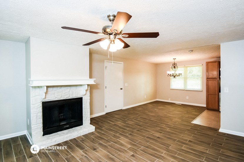 a living room with a fireplace and a ceiling fan