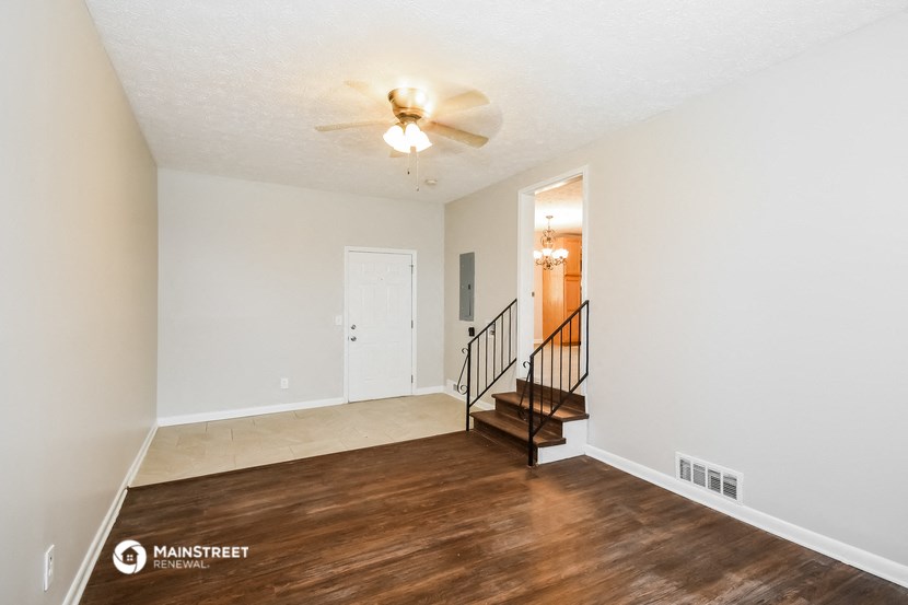 the spacious living room with hardwood flooring and a ceiling fan
